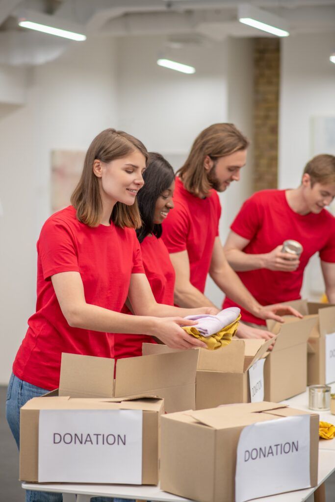 Group of young volunteers packing clothing donations into boxes